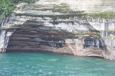 the water is crystal blue and clear at this point in the cliff face, with trees growing on it's sides