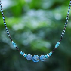 Petite beads of reconstituted turquoise and Karen hill tribe silver flank a faceted pendant of three dyed jasper stones for an elegant accessory that captures the beauty of natural waters. Sareeyakarn designs this necklace stringing the beads on a length of braided cord. It closes with a silver clasp. Leather Statement Necklace, Beaded Macrame, Beaded Chandelier Earrings, Macrame Pendant, Unique Pendant Necklace, Fine Silver Jewelry, Hill Tribe Silver, Gemstone Beaded Necklace, Beaded Pendant Necklace