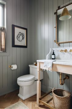 a white toilet sitting next to a wooden counter top in a bathroom under a mirror