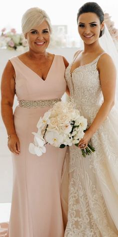 two women standing next to each other wearing dresses and holding bouquets in their hands