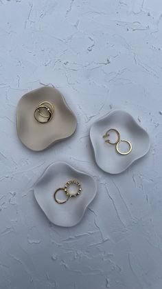 three white dishes with gold rings sitting on top of each other in front of a gray background