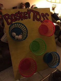 a sign that says basket toss with four baskets in front of it and stuffed animals on the floor