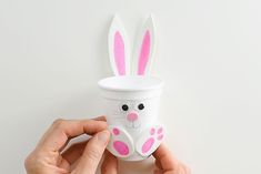 a hand holding a cup with bunny ears on it