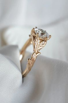 a close up view of a ring with a leaf design on the side and a diamond in the middle