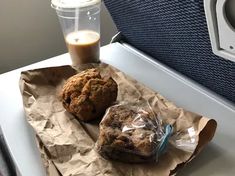 two muffins sitting on top of a piece of paper next to a cup of coffee