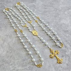 three rosarys with gold cross and white pearls