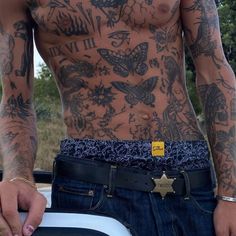 a man with tattoos on his chest and jeans