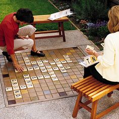 two people playing a game on a tile floor in a garden with wooden benches and tables