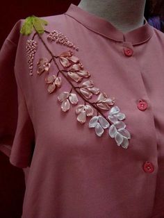 a pink dress with white flowers and green leaves on the front, along with buttons