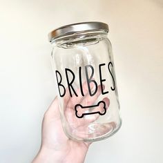 a hand holding a glass jar with the words bribes on it and a dog bone