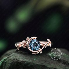 a ring with an oval blue topazte surrounded by leaves and diamonds on a rock