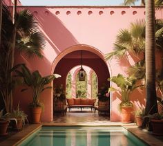 an outdoor pool surrounded by palm trees and potted plants in front of a pink wall