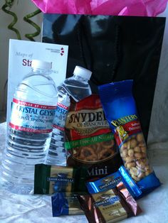 a black bag filled with lots of different types of food and drinks next to a bottle of water