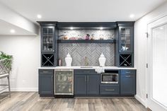 a kitchen with gray cabinets and white counter tops is shown in this image, there are two vases on the shelves