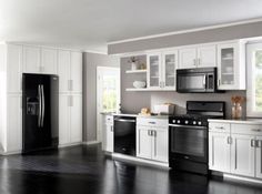 a kitchen with white cabinets and black appliances