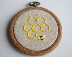 a close up of a embroidery on a piece of cloth with a bee and honeycomb