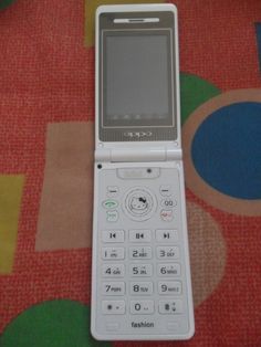 an old cell phone sitting on top of a colorful tablecloth with circles around it