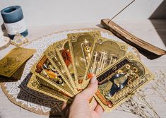 a person holding some cards on top of a table next to a vase and other items