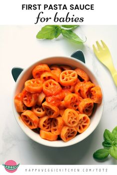 a white bowl filled with pasta and sauce on top of a table next to a yellow fork