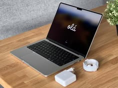 an open laptop computer sitting on top of a wooden table next to a charger