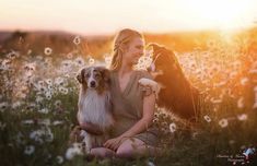 a woman sitting in a field with two dogs