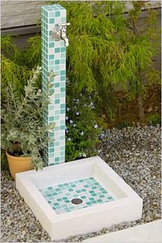 a white sink sitting in the middle of a garden next to a tall green pole