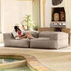 a woman sitting on top of a couch next to a pool