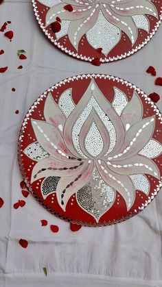 two red and white plates sitting on top of a table covered in rose petal petals