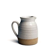 a white and brown pitcher sitting on top of a table