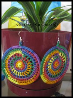 a pair of colorful crochet earrings sitting on top of a potted plant