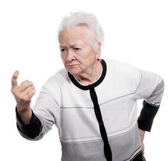 an old woman with white hair and black tie making a hand gesture while standing against a white background