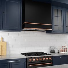 a kitchen with dark blue cabinets and white tile backsplash, copper trim on the hood