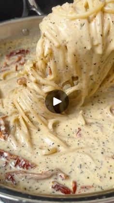 a ladle full of pasta and sauce being stirred