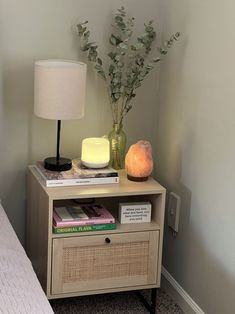 a nightstand with books and a lamp on it