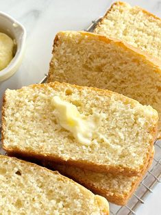 four slices of bread sitting on top of a cooling rack next to a bowl of butter