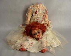 an old doll with red hair sitting on top of another doll's head and body