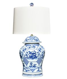 a blue and white porcelain lamp with a white shade on the top, against a white background