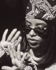 a woman wearing sunglasses and a bandana is holding her hands up to the camera