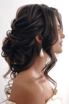 a woman with long hair wearing a white dress and pearls in her hair is looking off to the side