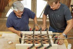 two men are working on an object made out of wood and metal pieces with tools attached to them