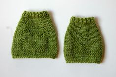 two green knitted mittens sitting next to each other