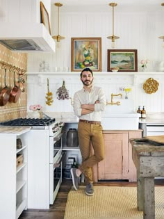 a man standing in the middle of a kitchen with his arms crossed and looking at the camera