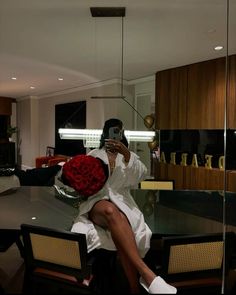 a woman sitting on top of a table holding a red rose