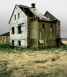 an old run down house sitting in the middle of a field with no grass on it