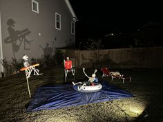 some skeleton figurines sitting on top of a blue tarp in front of a house