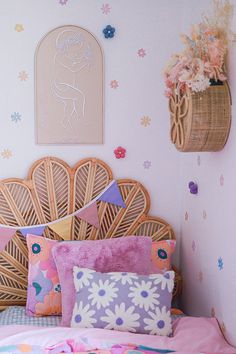 there is a bed with pink and blue pillows in the room that has flowers on the wall