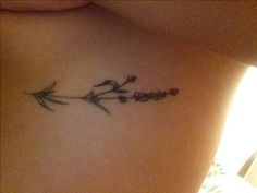 the back of a woman's stomach with an arrow and flowers tattoo on it