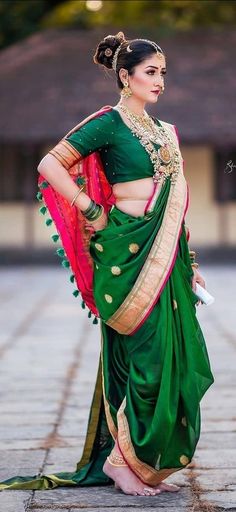 a woman in a green and red sari with her hands on her hips, posing for the camera