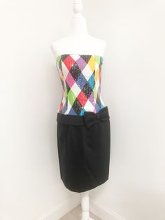 This is a strapless dress from Jenna Benjamin, USA. The bodice of the dress is a colorful harlequin pattern that is completely covered in clear sequins, giving it a lovely shine. The skirt is solid black and the low waist is accented with a bow. The dress zips in the back and is boned in the bodice. Size tag 6. Check measurements carefully, no stretch. Measurements taken with dress laying flat and doubled where appropriate. In order to determine fit we recommend comparing measurements with an it Elegant Multicolor Strapless Evening Dress, Retro Multicolor Mini Dress For Party, Elegant Multicolor Strapless Dress, Multicolor Fitted Strapless Dress, Multicolor Strapless Dress For Party Season, Multicolor Strapless Dress For Night Out, Elegant Fitted Multicolor Strapless Dress, Multicolor Fitted Strapless Dress For Cocktail, Multicolor Fitted Strapless Cocktail Dress