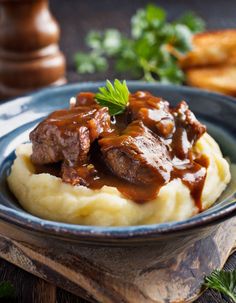 a blue plate topped with mashed potatoes covered in gravy and garnished with parsley